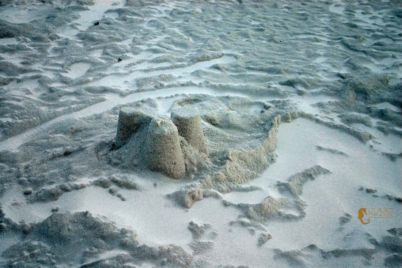 A ruin of a sandcastle with a dusting of powdered sand.